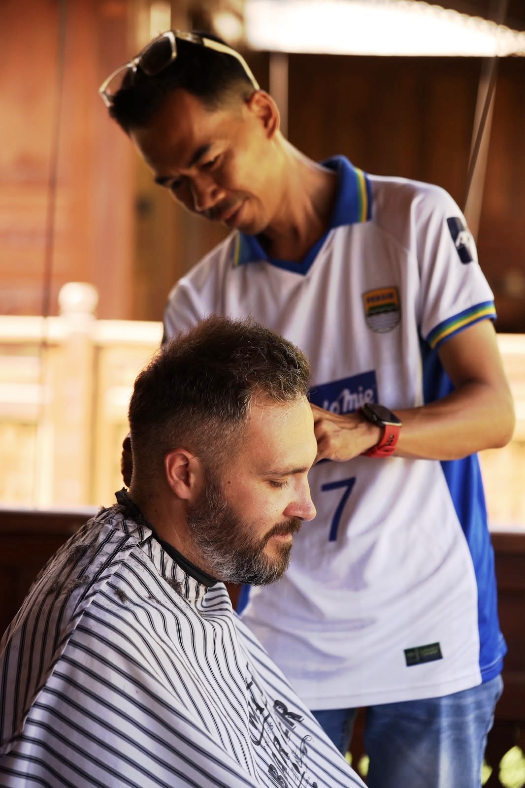 Danz carefully cutting a client's hair during a home visit