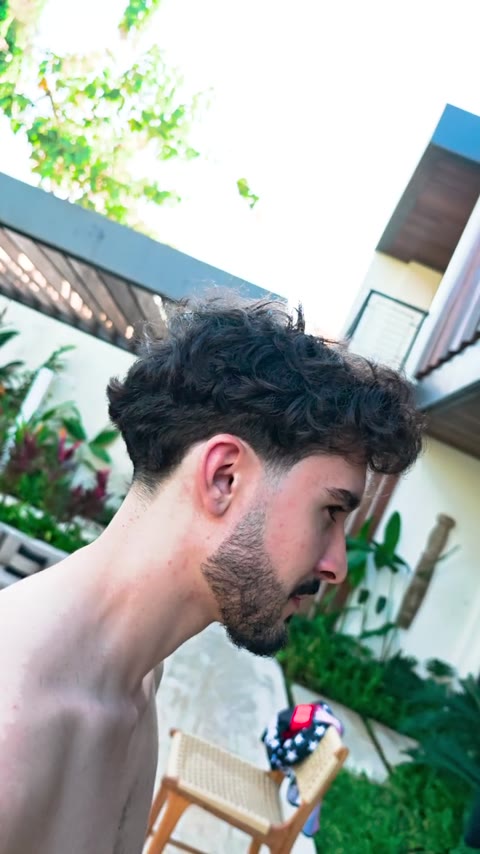 Curly hair with a tapered side and shaped beard